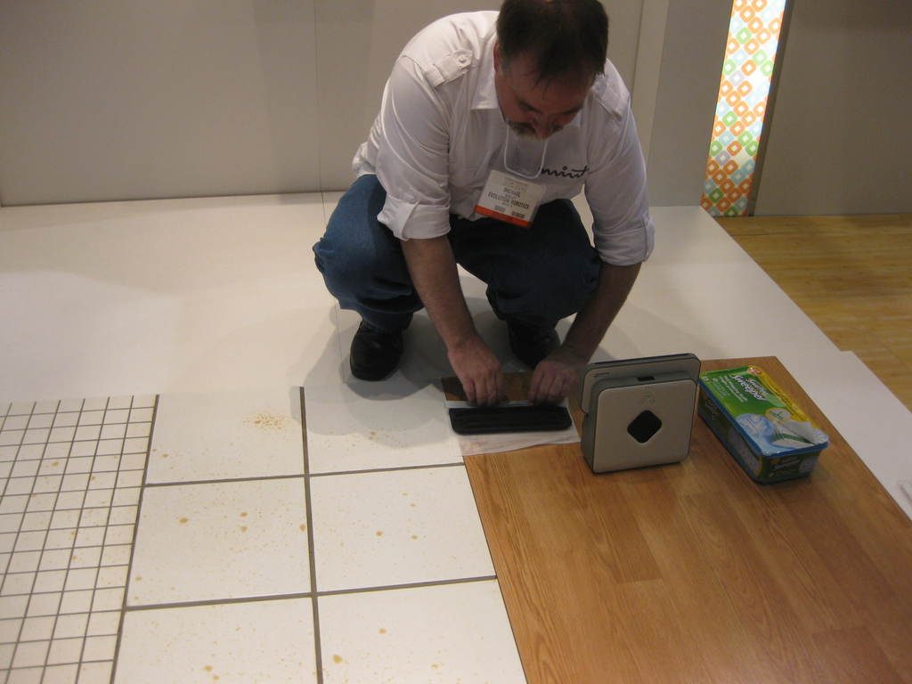 A floor partly laid in warm wood planks beside old white tiles